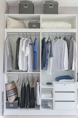 clothes hanging on rail in modern white wardrobe