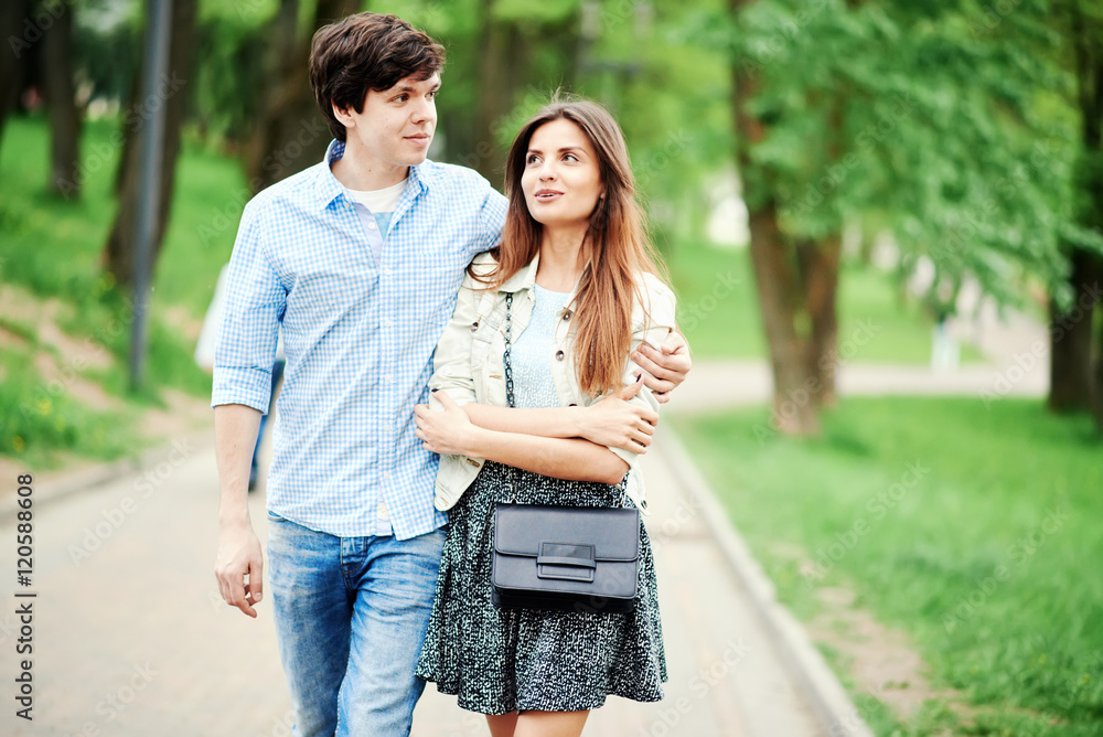 Fototapeta premium Young happy couple walking in the park in the summer and hugs