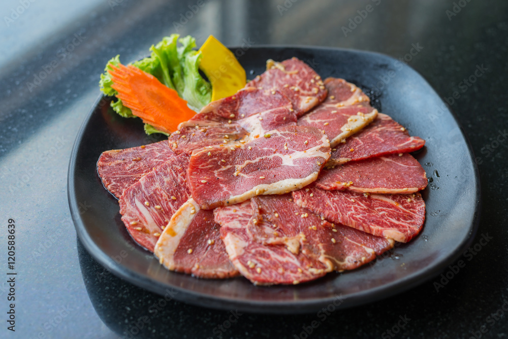 Raw beef slice for barbecue or Japanese style yakiniku on black Raw beef slice for barbecue or Japanese style yakiniku on black
