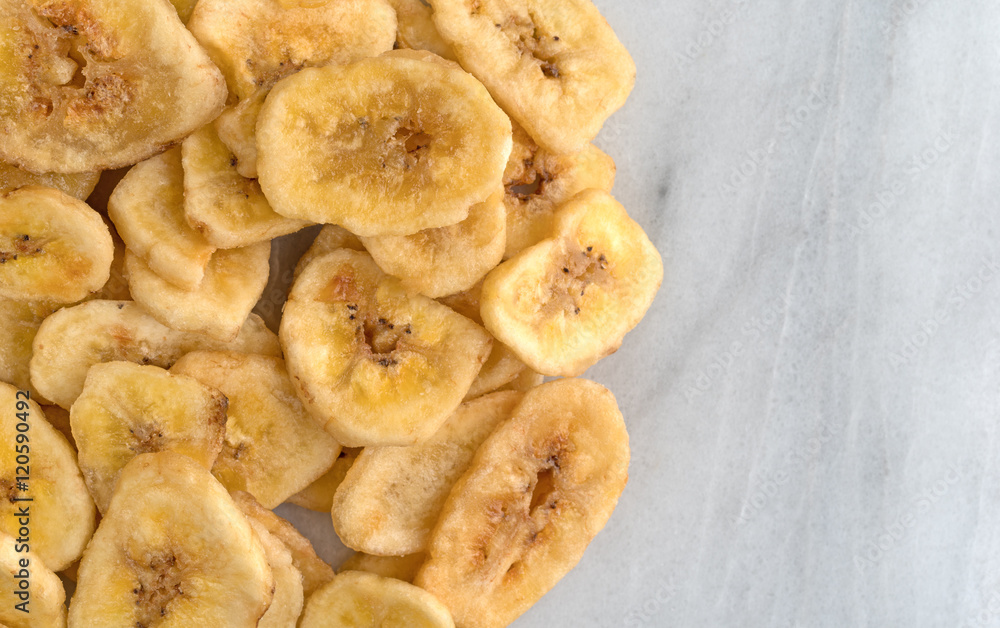 Dried bananas on a marble cutting board top close view. Dried bananas on a marble cutting board top close view.
