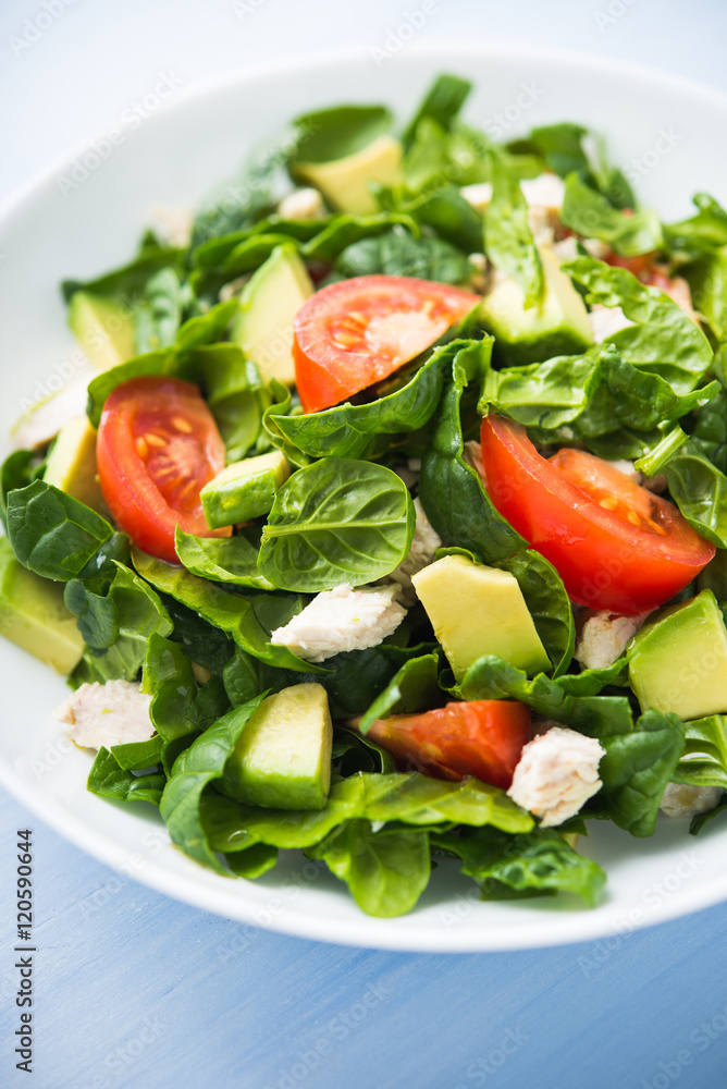 Fresh healthy salad with chicken, tomatoes, spinach and avocado on blue wooden background close up. Health and food. Fresh healthy salad with chicken, tomatoes, spinach and avocado on blue wooden background close up. Health and food.