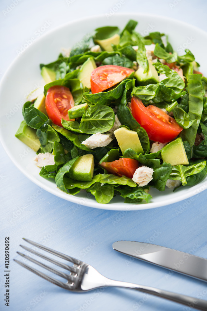 Fresh healthy salad with chicken, tomatoes, spinach and avocado on blue wooden background close up. Health and food. Fresh healthy salad with chicken, tomatoes, spinach and avocado on blue wooden background close up. Health and food.