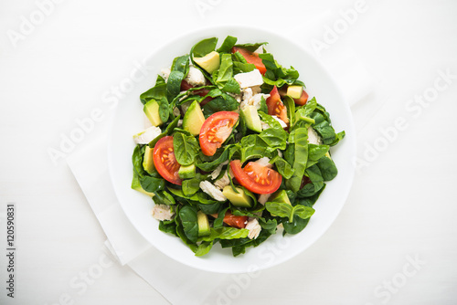 Fresh salad with chicken, tomatoes, spinach and avocado on white wooden background top view. Healthy food.