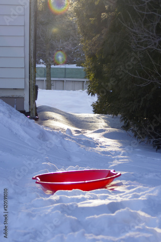 red saucer sled in winter backyard 