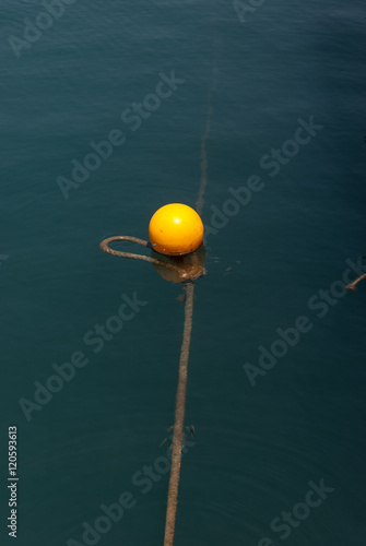 Yellow buoy on calm blue sea water surface