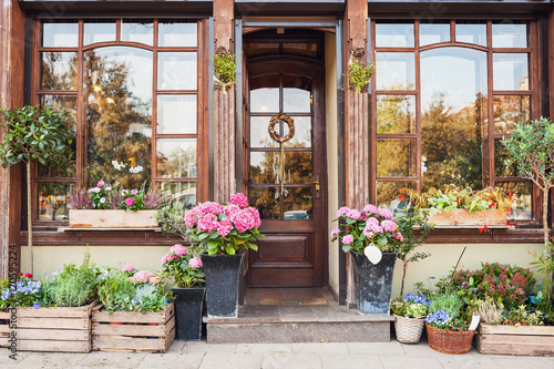 Flower store or cafe entrance decorated with flowers. Rustic style concept. Beautiful design elements