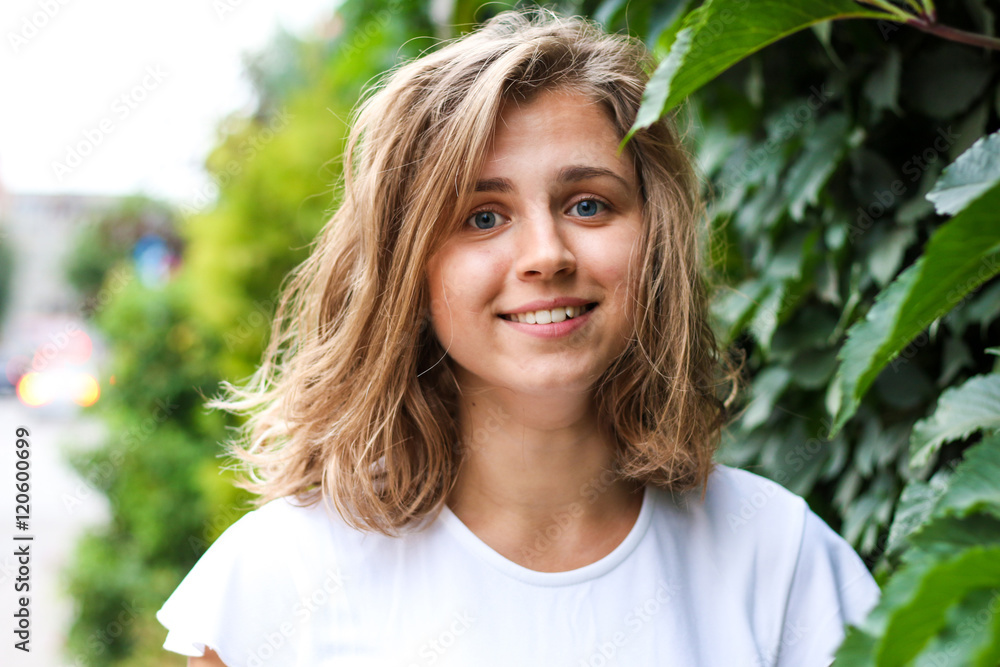 Portrait of a beautiful young woman on a background of green leaves, summer outdoors Portrait of a beautiful young woman on a background of green leaves, summer outdoors