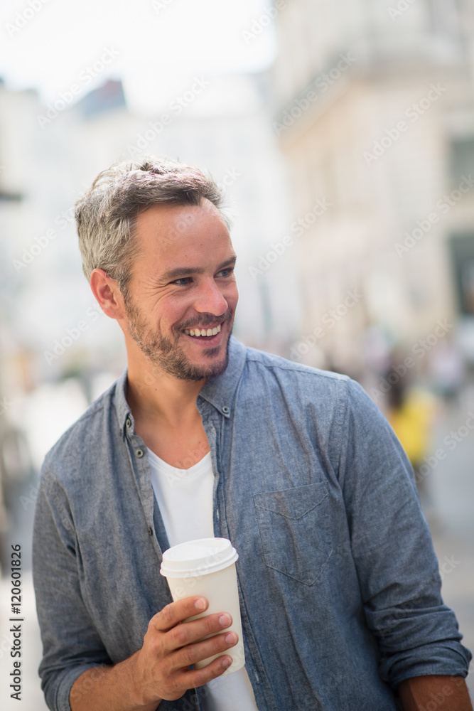 man walking on the streets with a take away coffee at hand man walking on the streets with a take away coffee at hand