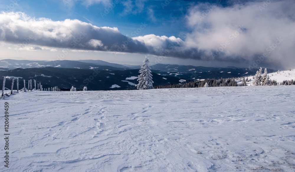 winter mountains panorama with blue sky and clouds from Schwarzriegel hill summit in Fischbacher Alpen mountain range in Styria