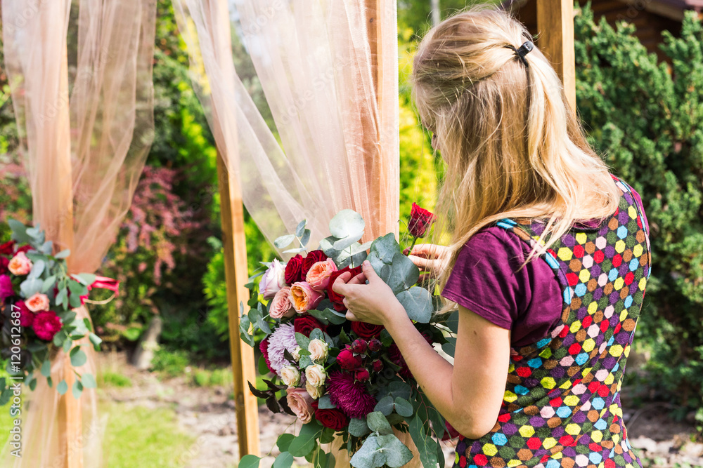 Naklejka premium Decorator working with flowers composition for wedding arch