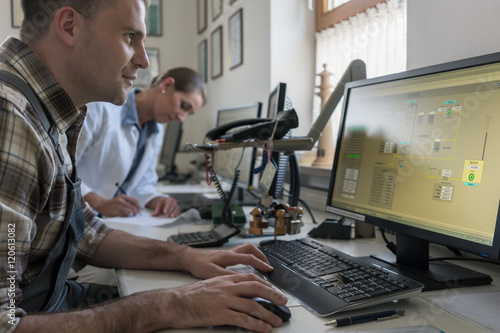 Man and woman in control room of water purification plant monitoring the technical processes