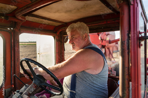 Farmer steering tractor during harvest in drivers cabin