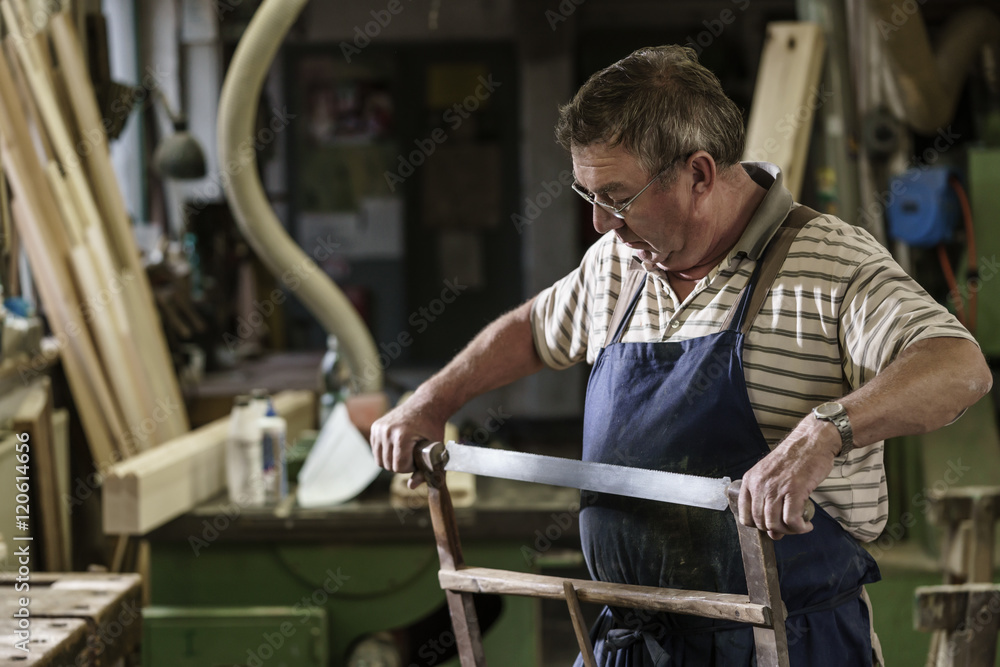 Craftsman in his wood workshop adjusting hacksaw Craftsman in his wood workshop adjusting hacksaw