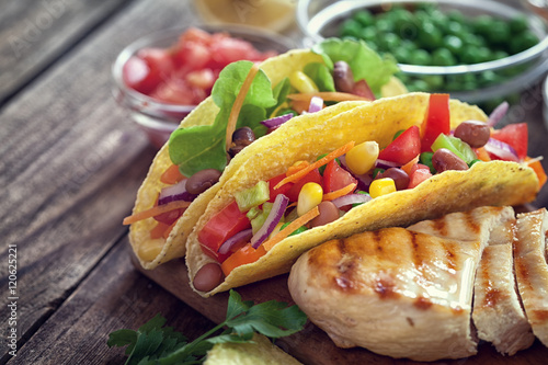 Mexican corn tortilla tacos with vegetables and grilled chicken on wooden background 