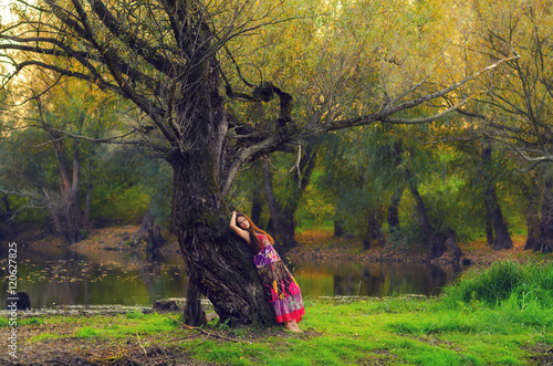 Elegant lady leaning on old tree on beautiful autumn day © Solid photos