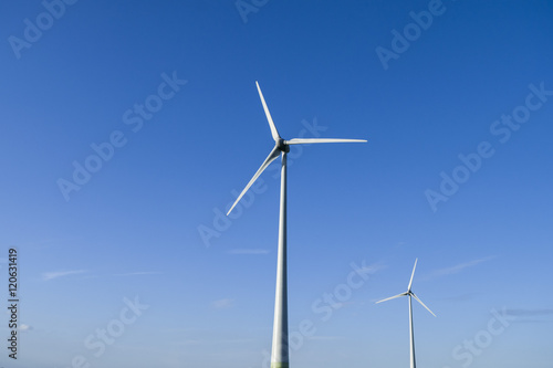 White windmills on blue sky background. Wind energy. 