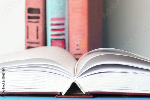 Open book, stack of colorful hardback books on light table. Back