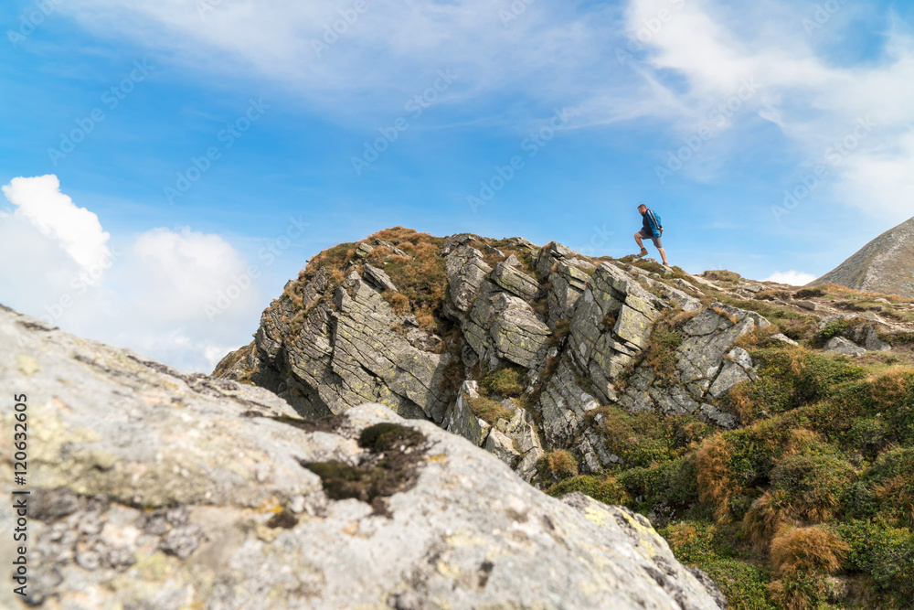 Tourist man climbs to peak of the rocky mountain Tourist man climbs to peak of the rocky mountain