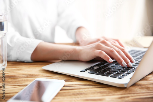 Woman working on computer at wooden desk © Africa Studio