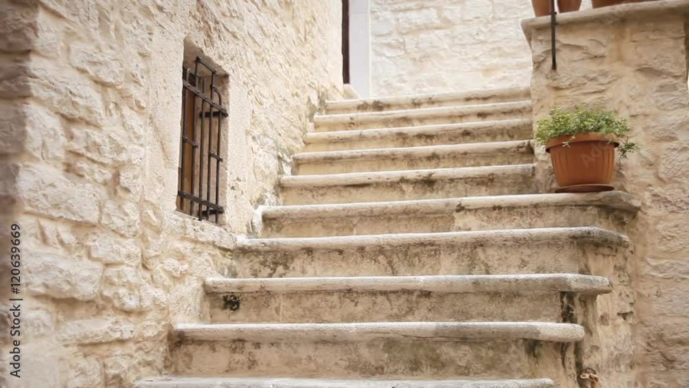 An old Italian town: a street with worn-out stairs, medieval houses, legs of some passerby. Archival context establishing shot.
An old Italian town: a street with worn-out stairs, medieval houses, legs of some passerby. Archival context establishing shot.