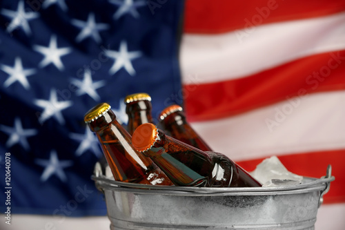 Bucket with cold beer bottles on American national flag background