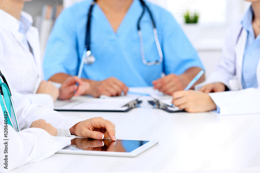 Group of doctors at medical meeting. Close up of physician using tablet computer. Group of doctors at medical meeting. Close up of physician using tablet computer.
