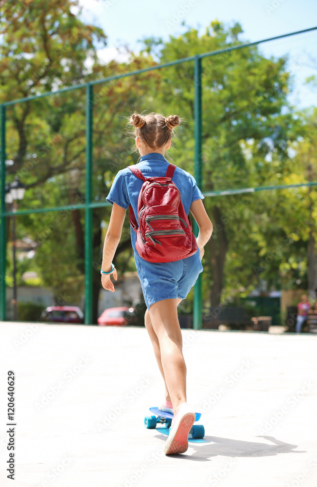 Cute young girl riding skateboard in sports ground Cute young girl riding skateboard in sports ground