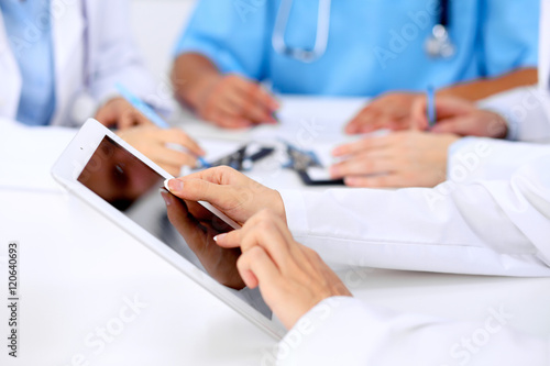 Group of doctors at medical meeting. Close up of physician using tablet computer.