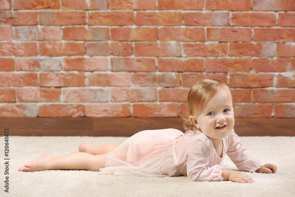 Fototapeta premium Little fashion-girl in pink dress posing on a brick wall background