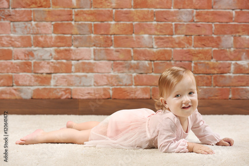 Little  fashion-girl  in pink dress posing on a brick wall background