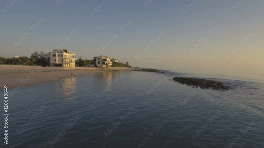 Beautiful aerial flying over beachfront property in South Florida at Dawn.  Amazing scenic ocean view with reef and clear water.