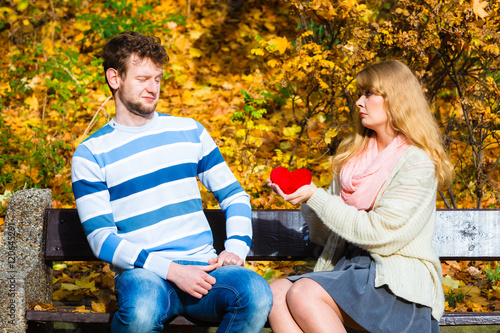 Woman confess love to man on bench in park.