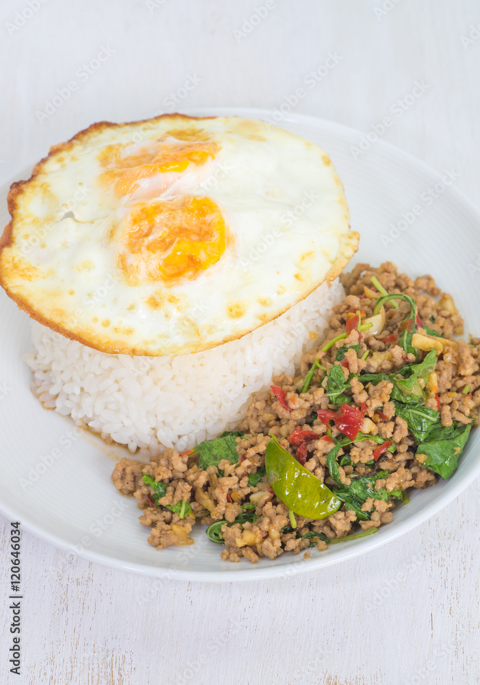 Steamed rice topped with fried egg and fried pork with basil leaves