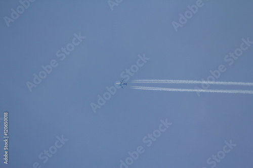 Airplane in the blue sky with condensation trail