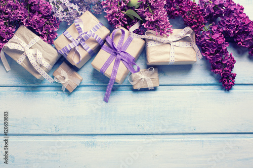 Many  festive gift boxes with presents  and llilac flowers on bl photo