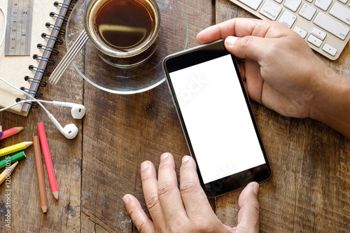 Smart phone with white blank empty screen on wood desk table in home office.