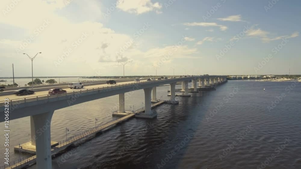 Aerial establishing shot of bridge with highway traffic over river in a coastal environment. Aerial establishing shot of bridge with highway traffic over river in a coastal environment.