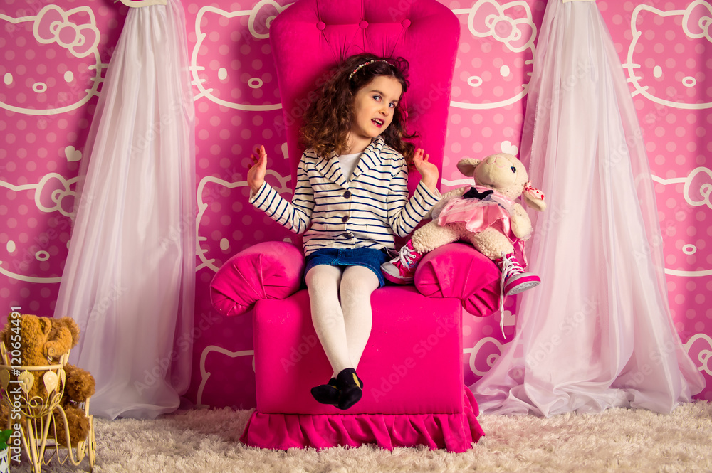 Fototapeta premium beautiful little curly girl in a big soft chair