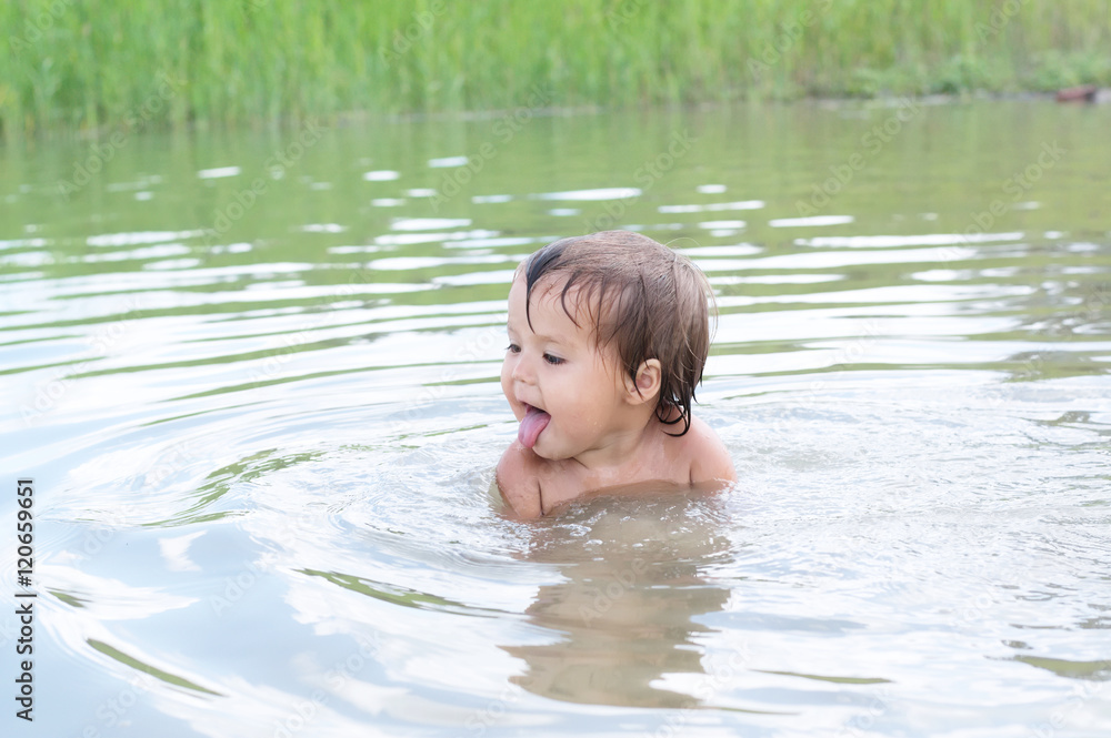 Cute girl swimming in the lake and having fun