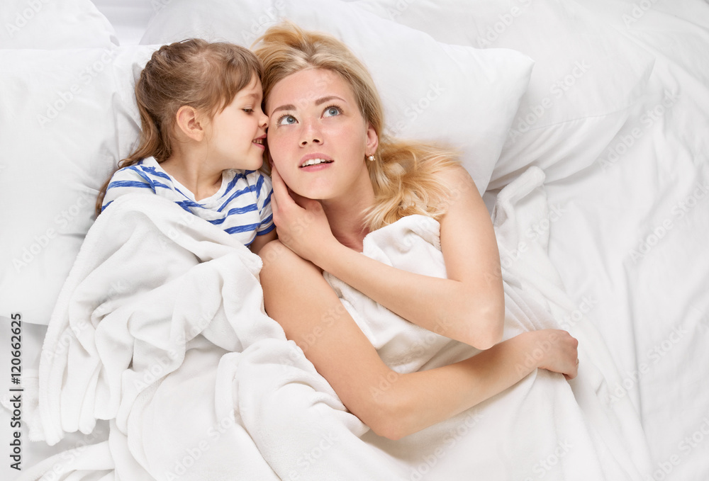 Mother and daughter whispering in bed Mother and daughter whispering in bed