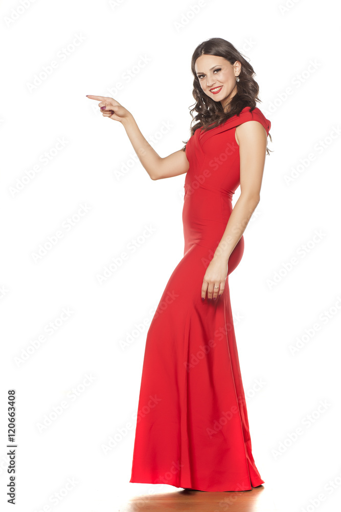 young beautiful woman posing in a long red dress and pointing young beautiful woman posing in a long red dress and pointing
