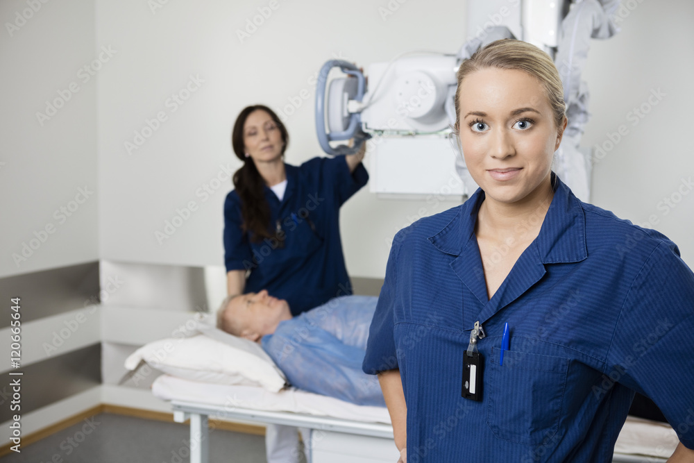 Obraz premium Young Doctor Standing While Colleague Taking Patient's Xray