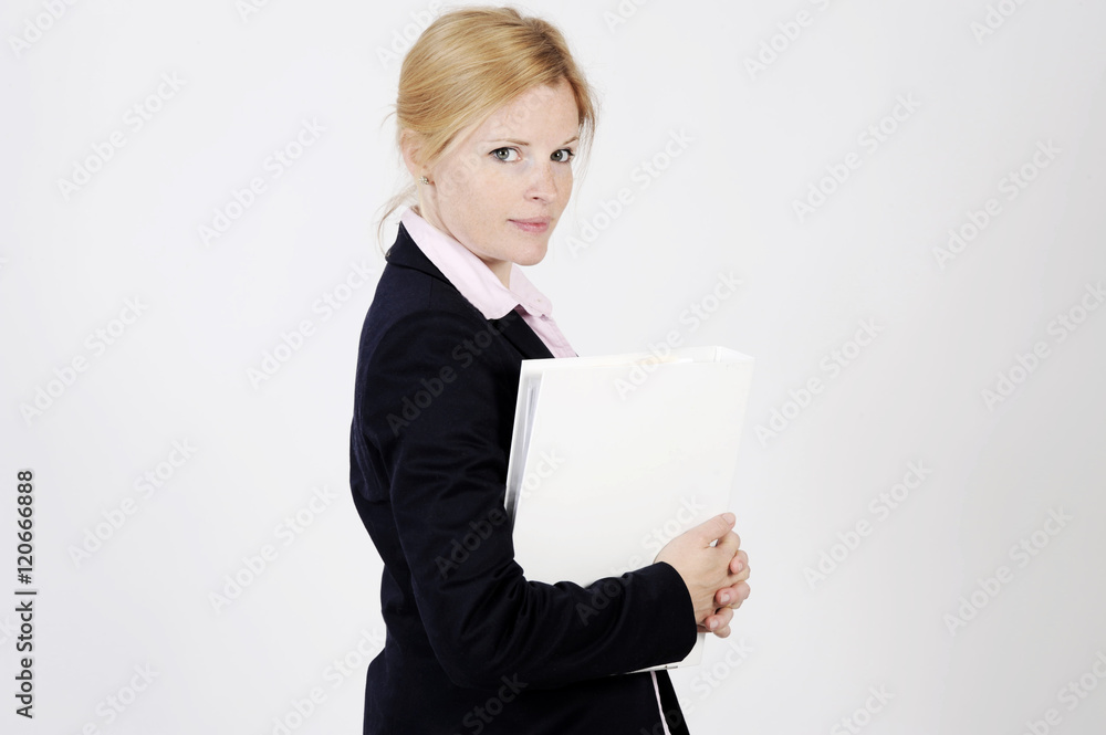 Young freckled businesswoman is standing with a portfolio, looking into the camera with an elegance smile. Studio shot with light background. Isolated. Young freckled businesswoman is standing with a portfolio, looking into the camera with an elegance smile. Studio shot with light background. Isolated.