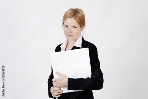 Young freckled businesswoman is standing with a portfolio, looking into the camera with an elegance smile. Studio shot with light background. Isolated.