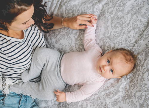 Young mom and her baby lying on bed at home.