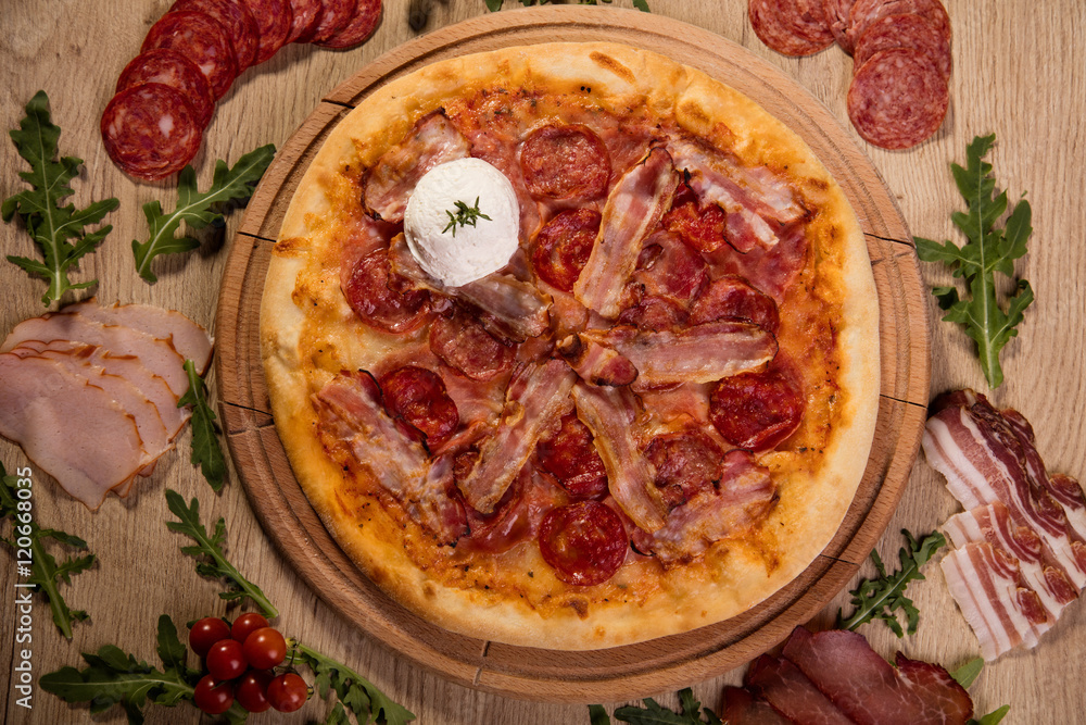 Pizza served on wooden board and raw ingredients on table Pizza served on wooden board and raw ingredients on table