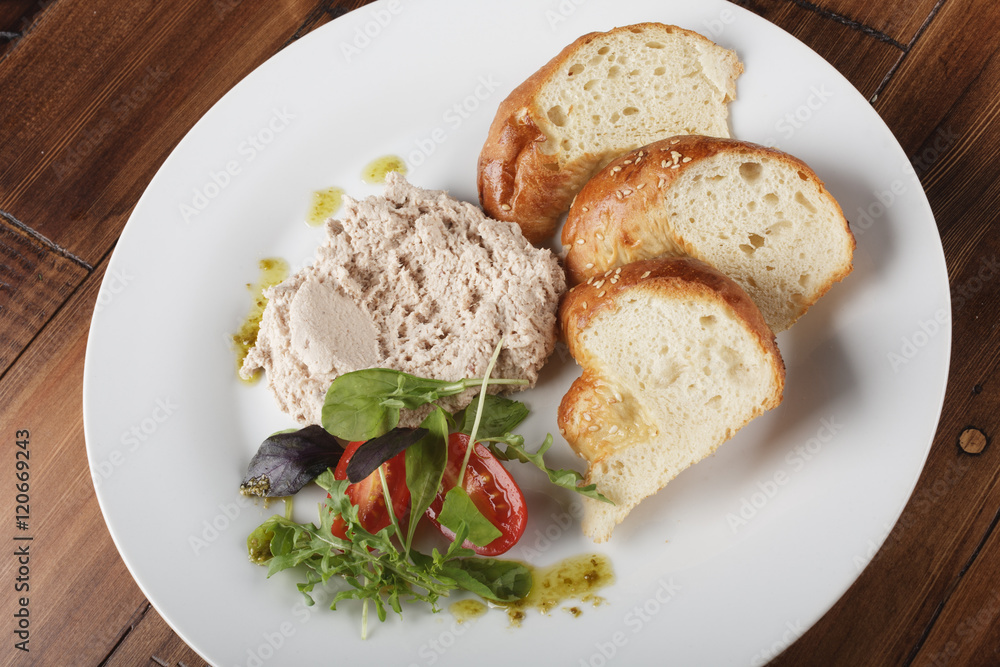 Rabbit pate with salad and bread in a white plate. White meat fillet. Wooden background. Rabbit pate with salad and bread in a white plate. White meat fillet. Wooden background.