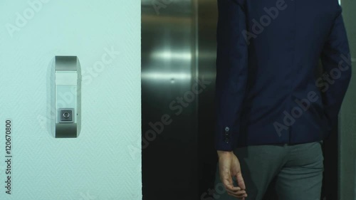 young businessman presses the Elevator button and enters it