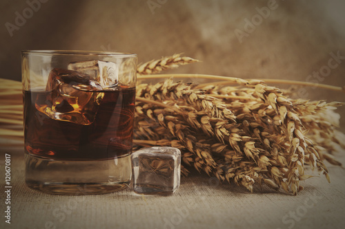 Glass whiskey on background with wheat straws toning photo photo