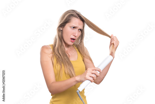 Young woman damage her hair with straightening iron